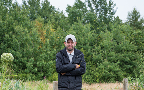 John stands besides a gate on a reserve